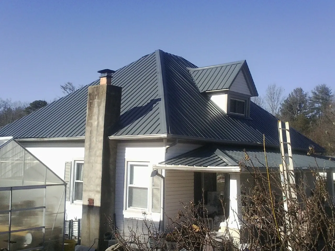 Dark blue standing seam metal roof on a white farmhouse with dormer — Slate & Tile Roof Repair by Roofing Brothers in O Fallon