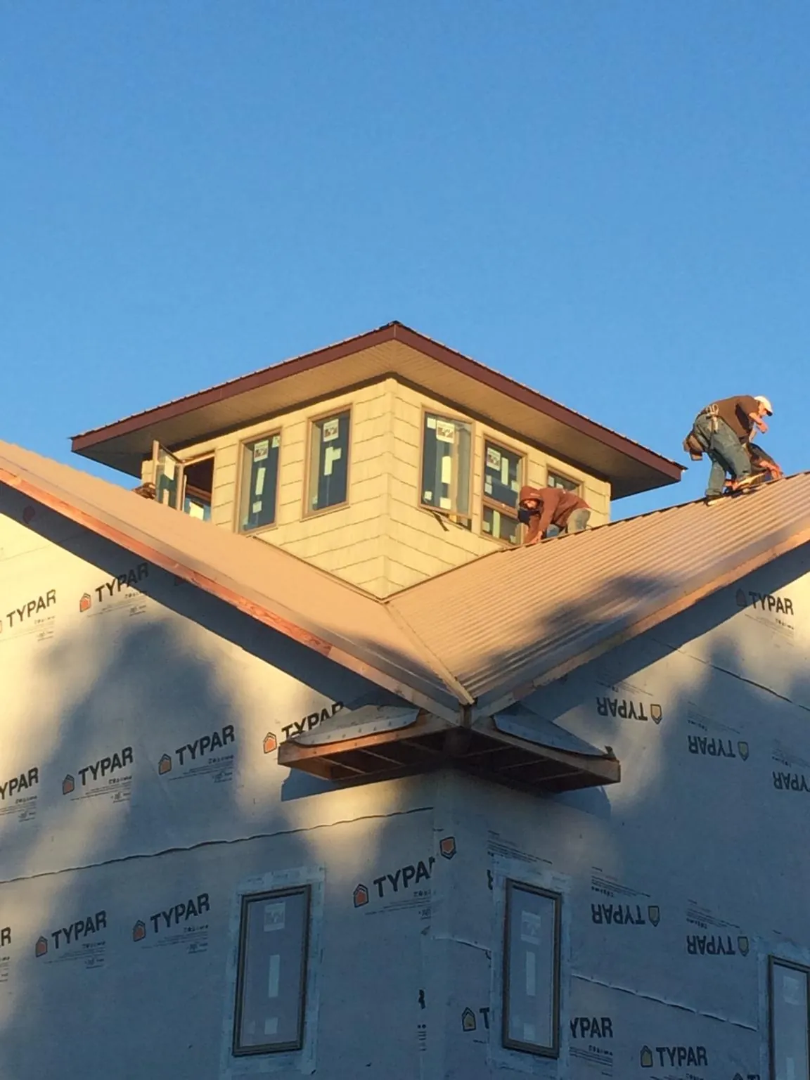 Roofers working around a rooftop cupola on a new metal roof at sunset — Roof Waterproofing in O Fallon by Roofing Brothers